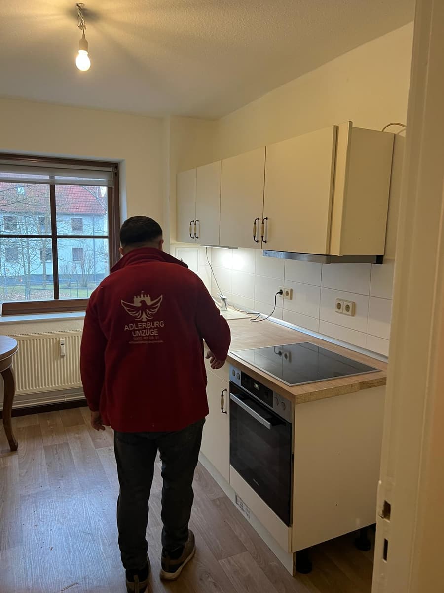 Mitarbeiter in roter Adlerburg-Jacke prüft die fertig aufgebaute Küche