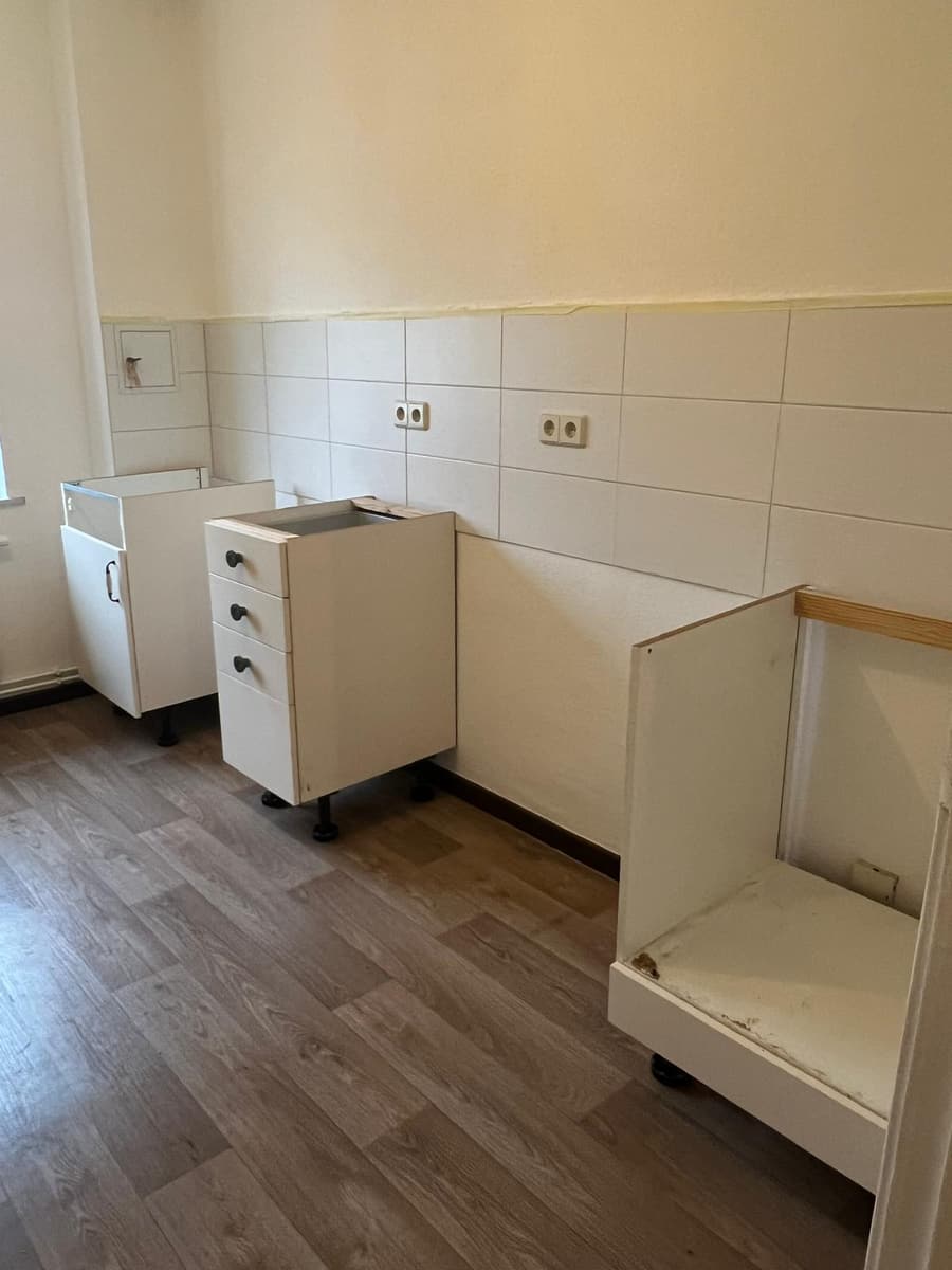 Küchenunterschränke stehen vor dem Aufbau noch ohne Arbeitsplatte an der gefliesten Wand