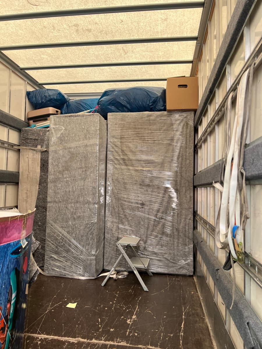Laderaum eines Umzugs-Lkw mit eingepackten Möbeln, Kartons und Spanngurten an der Wand