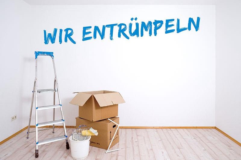 Ausgeräumtes Zimmer mit Leiter und einigen Kartons, an der Wand steht „Wir entrümpeln“