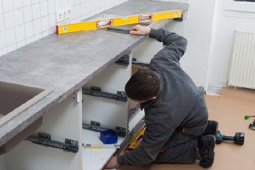 Handwerker prüft mit einer Wasserwaage, ob eine Küchenarbeitsplatte gerade liegt